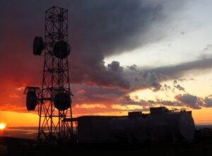 A GCI telecommunications tower in rural Alaska, silhouetted by a fiery sunset