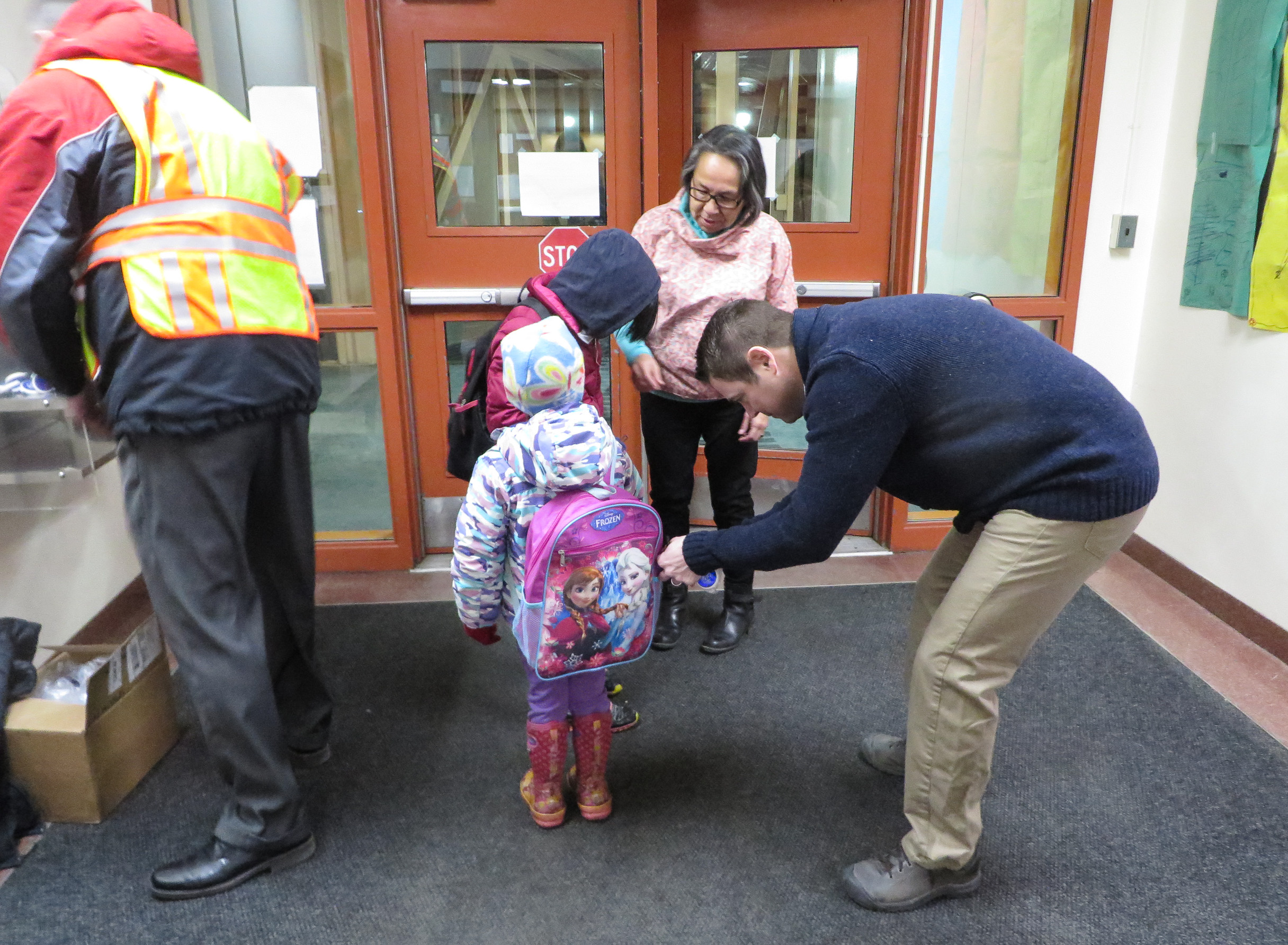 Superintendent Shawn Arnold helps a student attach a reflector keychain to her backpack. Photo: Laura Kraegel, KNOM.