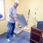 Jake helped lay new carpet tiles, replacing the flooring made thread-bare from decades of use. Photo: Ric Schmidt, KNOM.