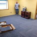 Jake helped lay new carpet tiles, replacing the flooring made thread-bare from decades of use. Photo: Ric Schmidt, KNOM.