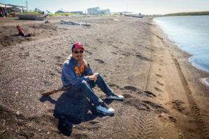 Summer in Stebbins, Alaska: resident Bernard Abouchuk sits on the beach in anticipation of a seal, which is hunted as a subsistence food. Photo: Emily Russell, KNOM.