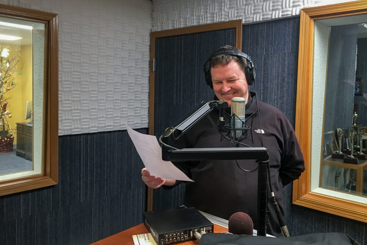 Father Jay Buhman at the microphone in KNOM's studios