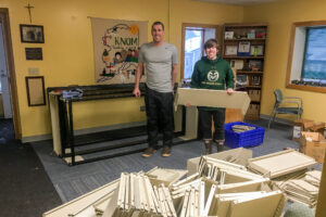 Nome Community Baptist Church Pastor Dan Heihn and volunteer Tyler Stup, sorting out the recycled shelves donated to KNOM.