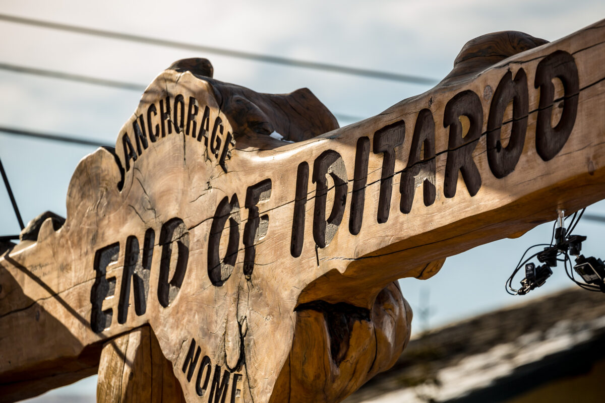 Detail of the Iditarod finish line in Nome, called the Burled Arch. Text reads “End of Iditarod,” etched in wood.