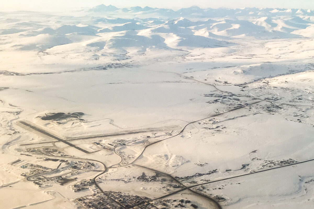 An aerial view of Nome, Alaska, its airport runways, and nearby mountains, covered in snow in late winter 2017.