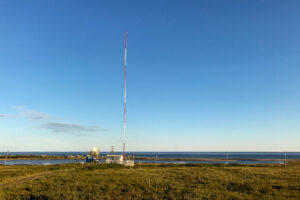 A radio station transmitter site on gently rolling tundra near the shoreline of the Bering Sea