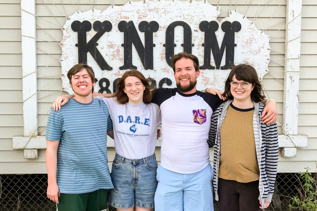 Tyler, Karen, Davis, and Lauren stand in front of the KNOM studio sign