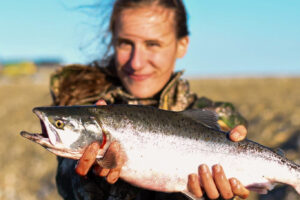 Woman holding a freshly-caught salmon outside on a sunny evening