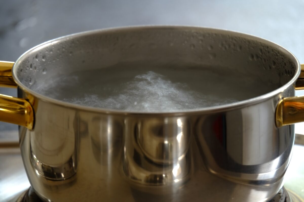 A stainless steel pot of boiling water on a stovetop.