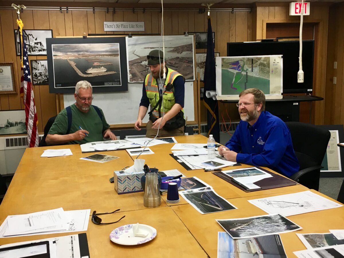 Chairman Jim West signs papers presented by Harbormaster Lucas Stotts at the end of a meeting of the Nome Port Commission.