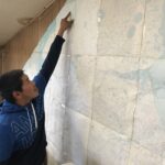 Corey Ningeulook points out where he hunts on gigantic map of Sarichef Island, taped to the wall of his office in Shishmaref. Photo: Grueskin/KNOM.