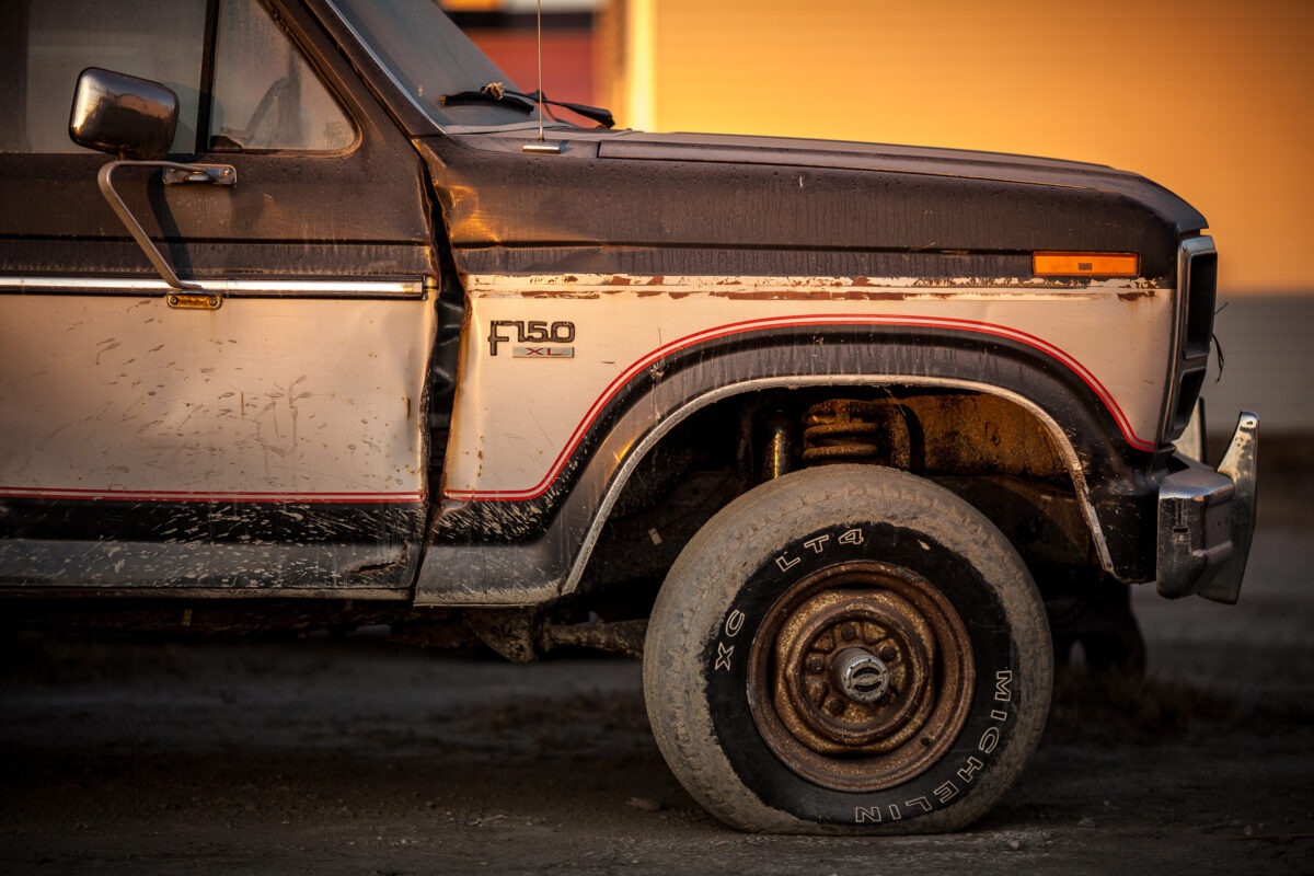 Side view of an old Ford pickup truck with rust marks and dust on its side.