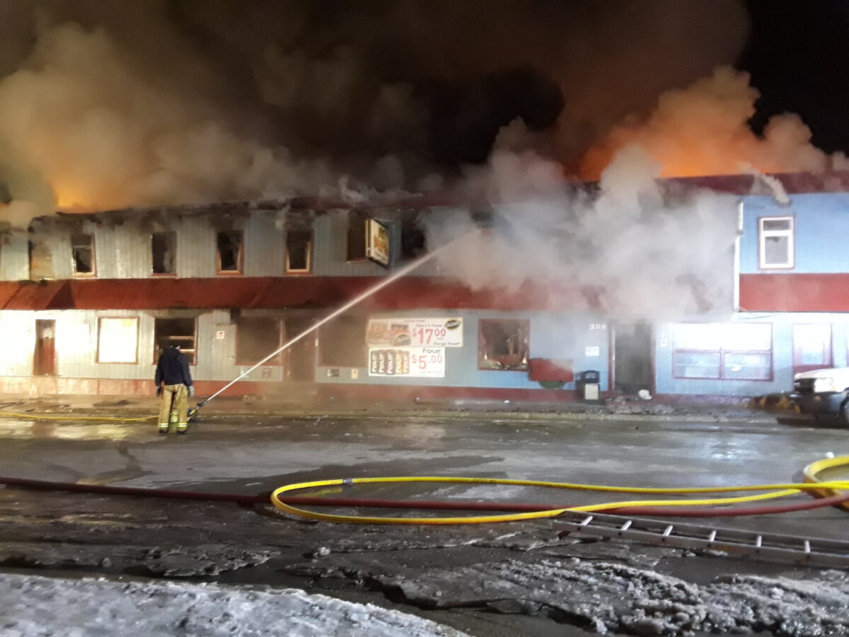 One Nome firefighter hoses down the Polaris Hotel on Tuesday morning after fire has been burning for more than 6 hours. Photo Credit: Davis Hovey, KNOM (2017)