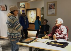 Artist Ron Senungetuk speaks with visitors to the Carrie M. McLain Memorial Museum. His work is featured in a special exhibit "Carving a Path of Cultural Continuity."