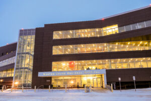 The Nome hospital at dusk, viewed from the front, with light streaming through its windows.