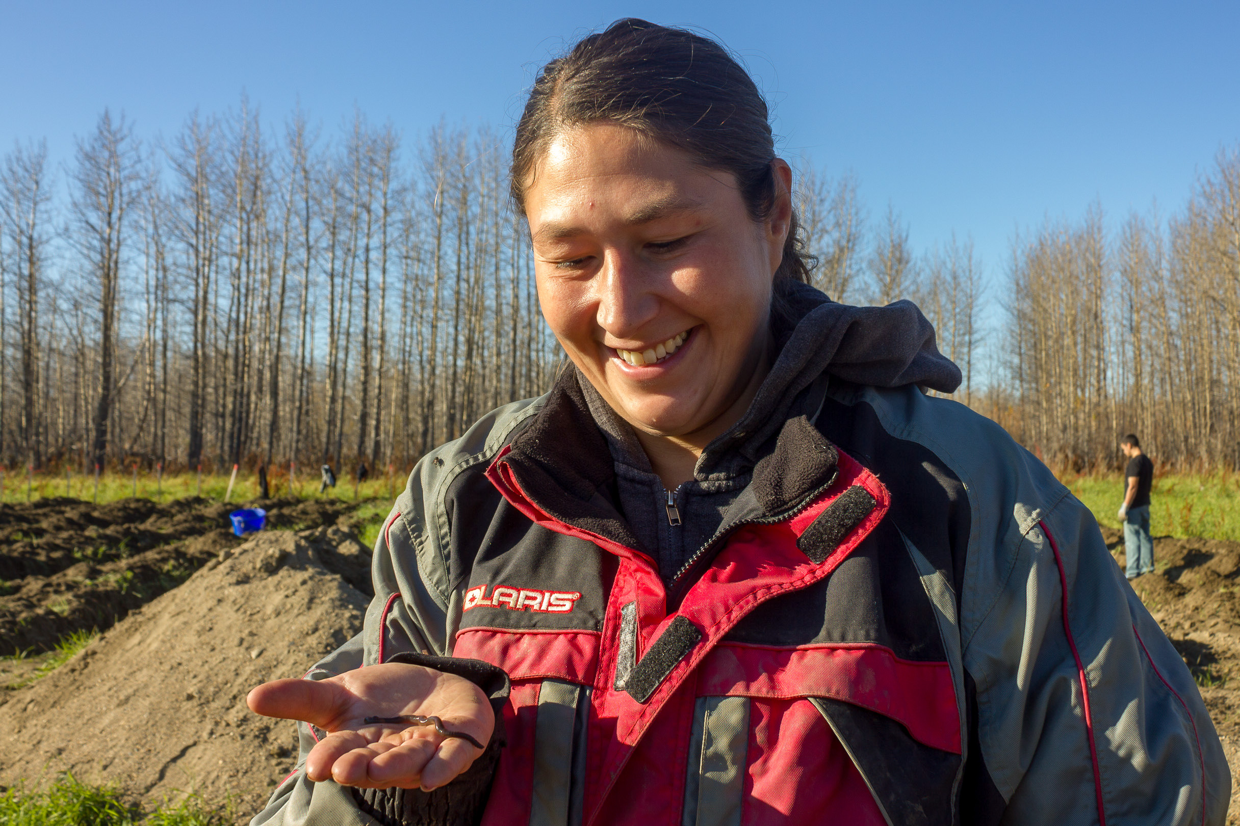 Farm manager smiles at an earthworm in her hand.