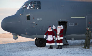 Santa and Mrs. Claus, dressed in full red and white suits, step out of the National Guard aircraft that transported them to St. Michael for Operation Santa Claus 2017.