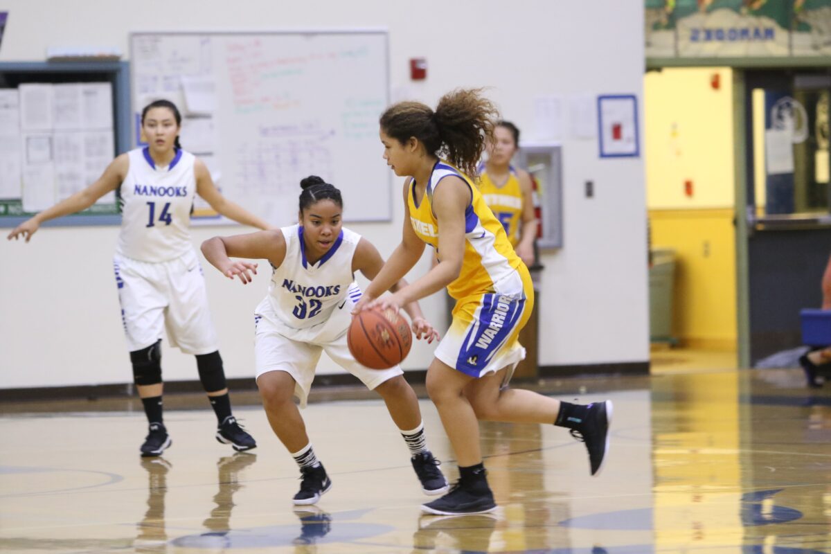 The Nanooks girls, in white, try to block a Bethel player with the ball, dressed in yellow