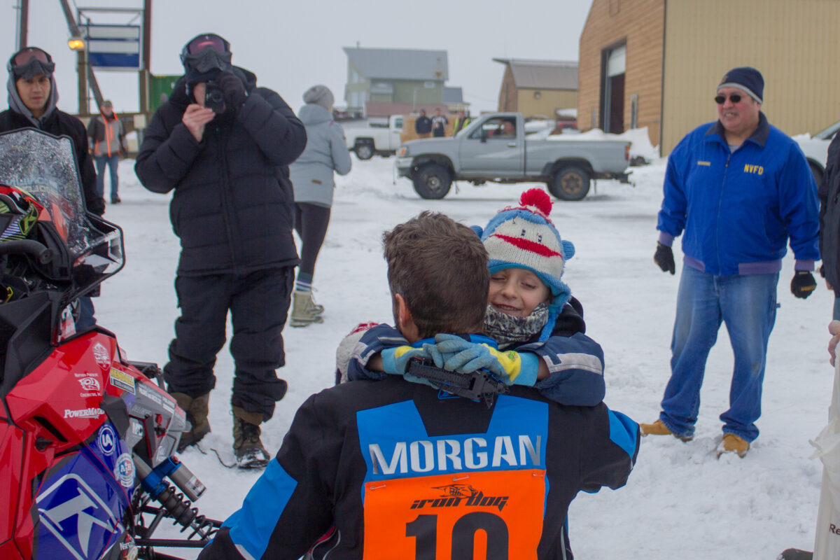 Nome's Mike Morgan hugs his daughter after crossing the halfway finish line in Nome (Photo: Karen Trop, KNOM)