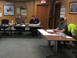 Commissioners Scot Henderson and Shane Smithhisler and Harbormaster Lucas Stotts review documents at a meeting of the Nome Port Commission in Feb. 2018.