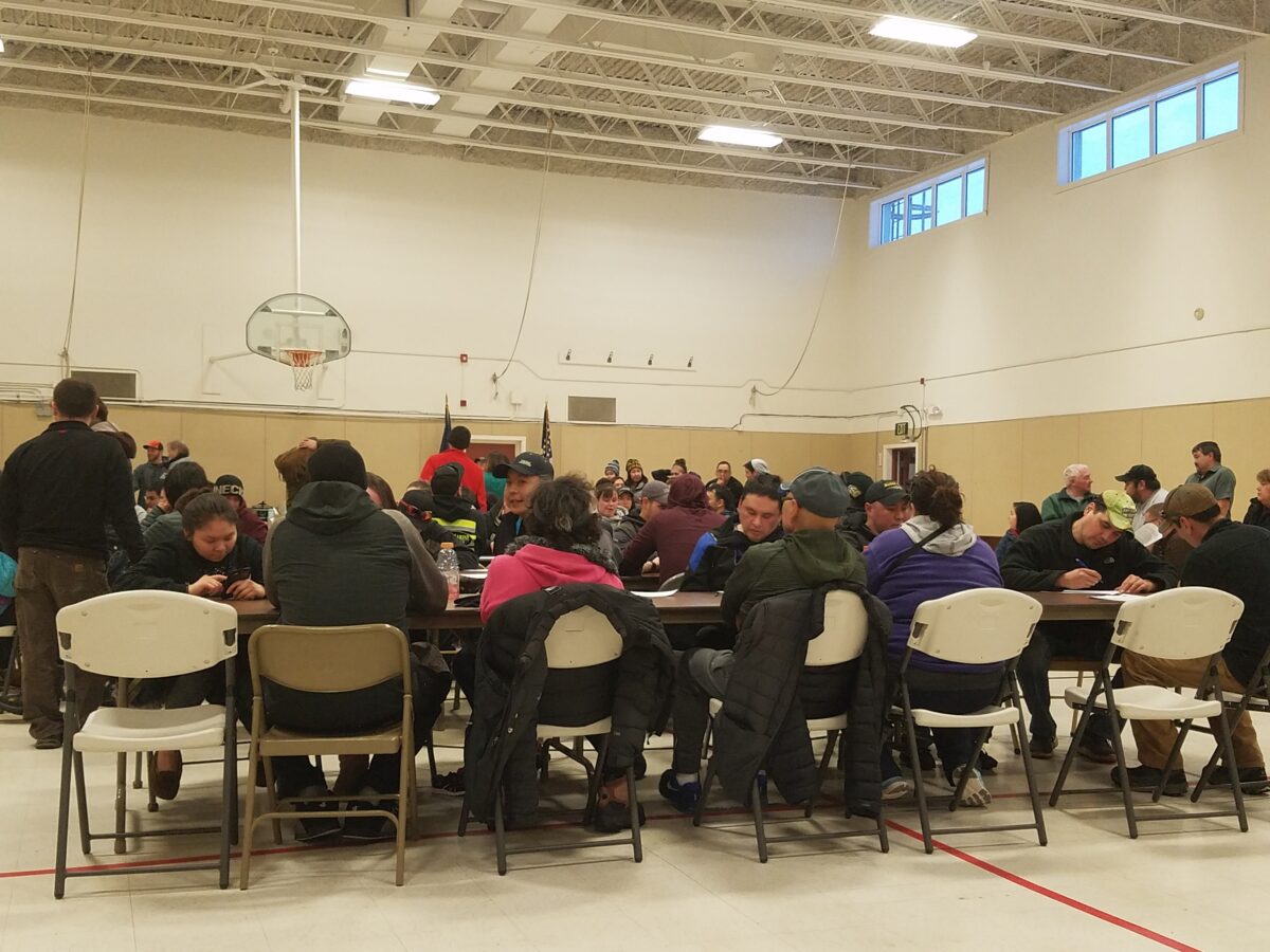 Racers sit at long tables set up in the Armory for the official sign-up of the 2018 Nome-Golovin Snowmachine Race.