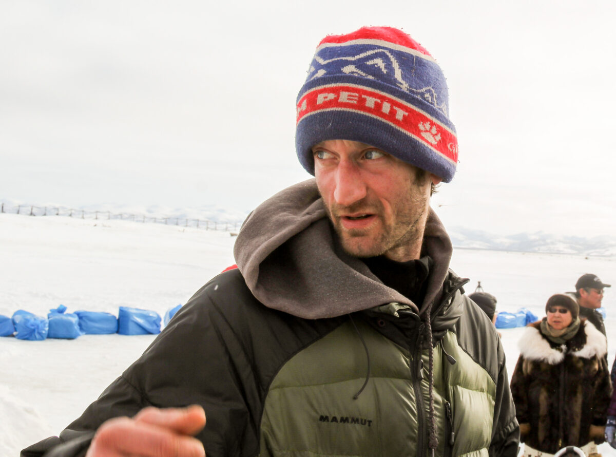 Iditarod musher Nic Petit, wearing "Petit" hat, looks around at the Unalakleet checkpoint