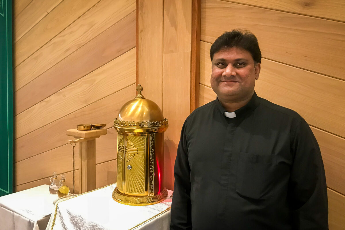 Priest stands inside church sanctuary