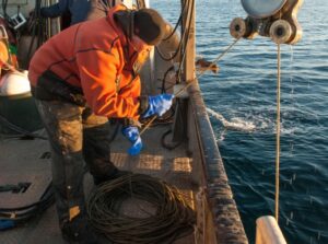 James Longley uses a pulley over the side of a fishing boat to retrieve a sound recorder from the Bering Sea.