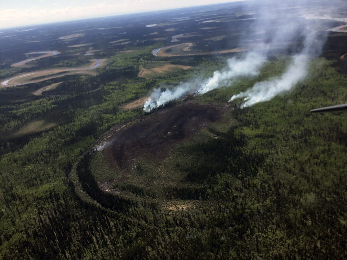 An aerial view of smoke rising from a wildfire in the Alaska wilderness.