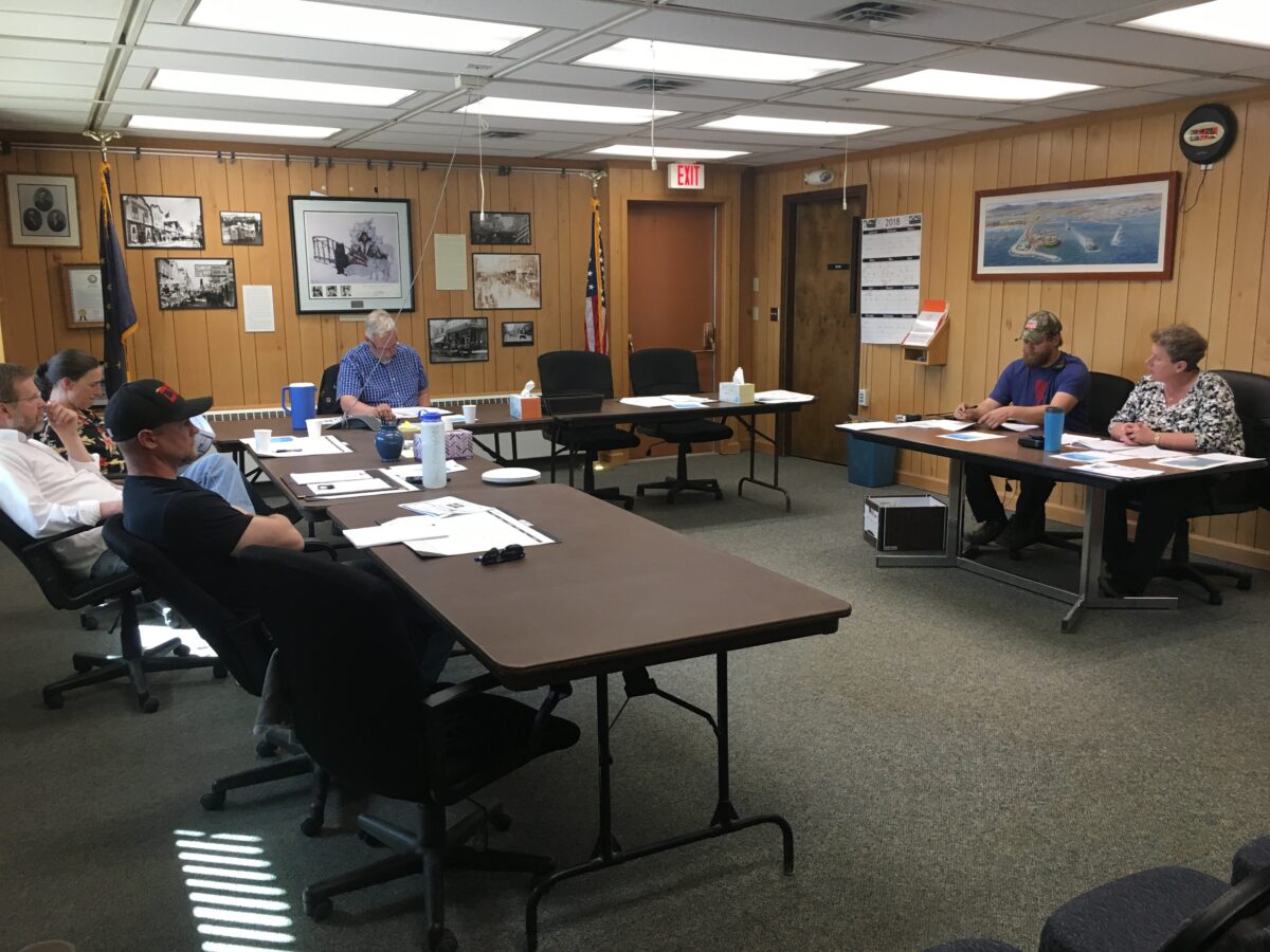 The Nome Port Commission sits around a semi-circle of tables in Council Chambers for their June meeting.