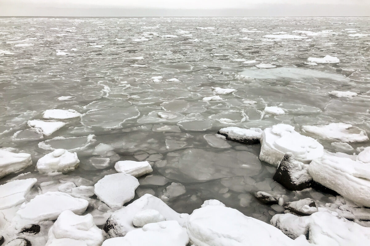 Scattered patches of thin sea ice as seen from the shoreline on a wintry day in a rural Alaska village.