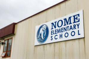 Exterior of Nome Elementary School, an off-white building with a smiling polar bear as its mascot.