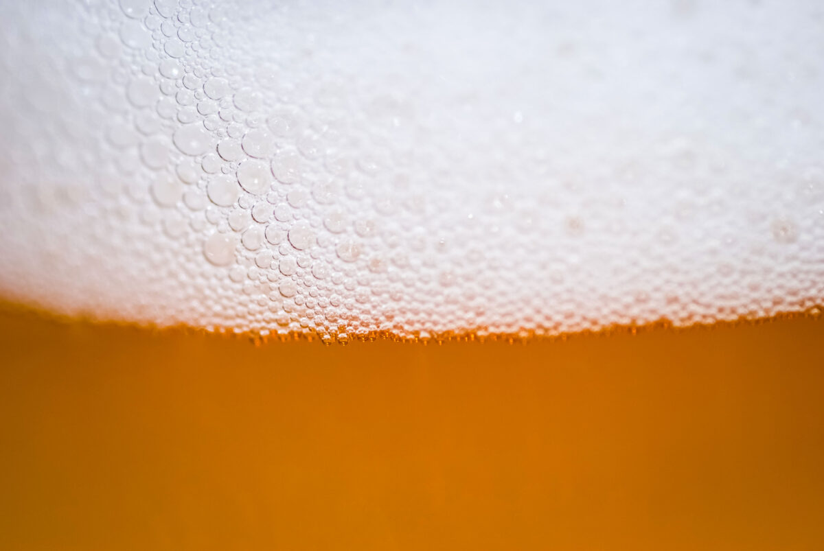Very close, macro view of beer poured into a glass.