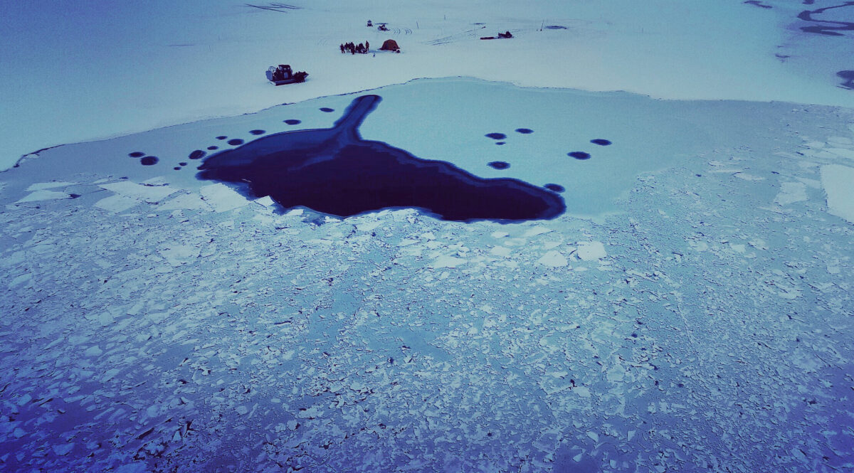 Aerial view of search-and-rescue efforts on frozen sea ice near a remote Alaska village.