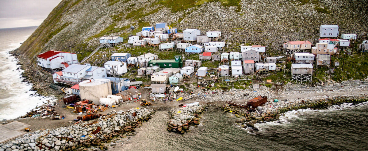 An aerial view of a small, coastal, island village nestled on the side of a hill.