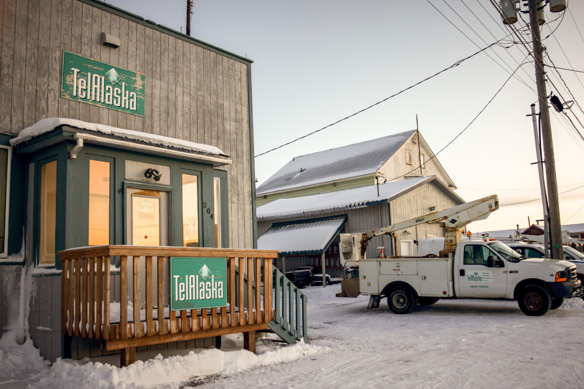 Exterior of wooden-clapboard building with TelAlaska signage in a snowy Alaska town.