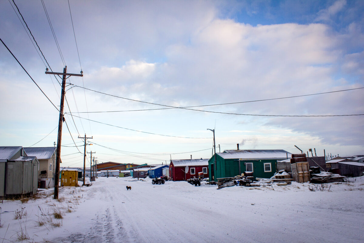 Snow-covered, rural Alaska street on a partly cloudy winter day.
