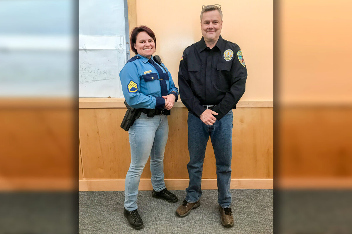 Two law enforcement officers in Nome stand smiling, wearing denim jeans.