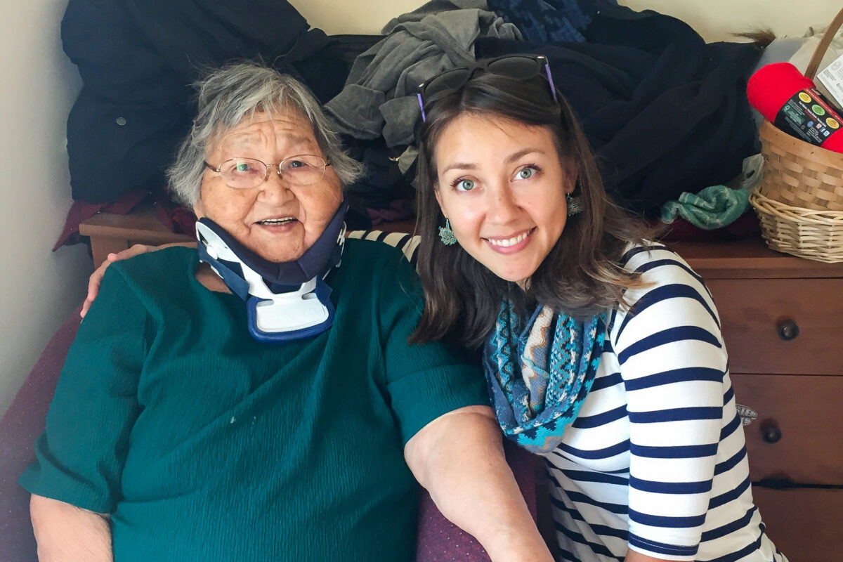 Elderly woman and young woman sit smiling, side-by-side