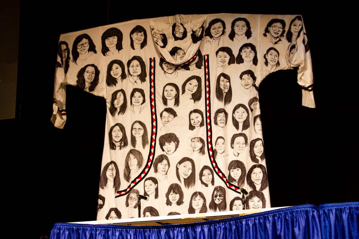 A photo of an art piece, a qaspeq with painted faces of women, hung at 2019 Alaska Federation of Natives.