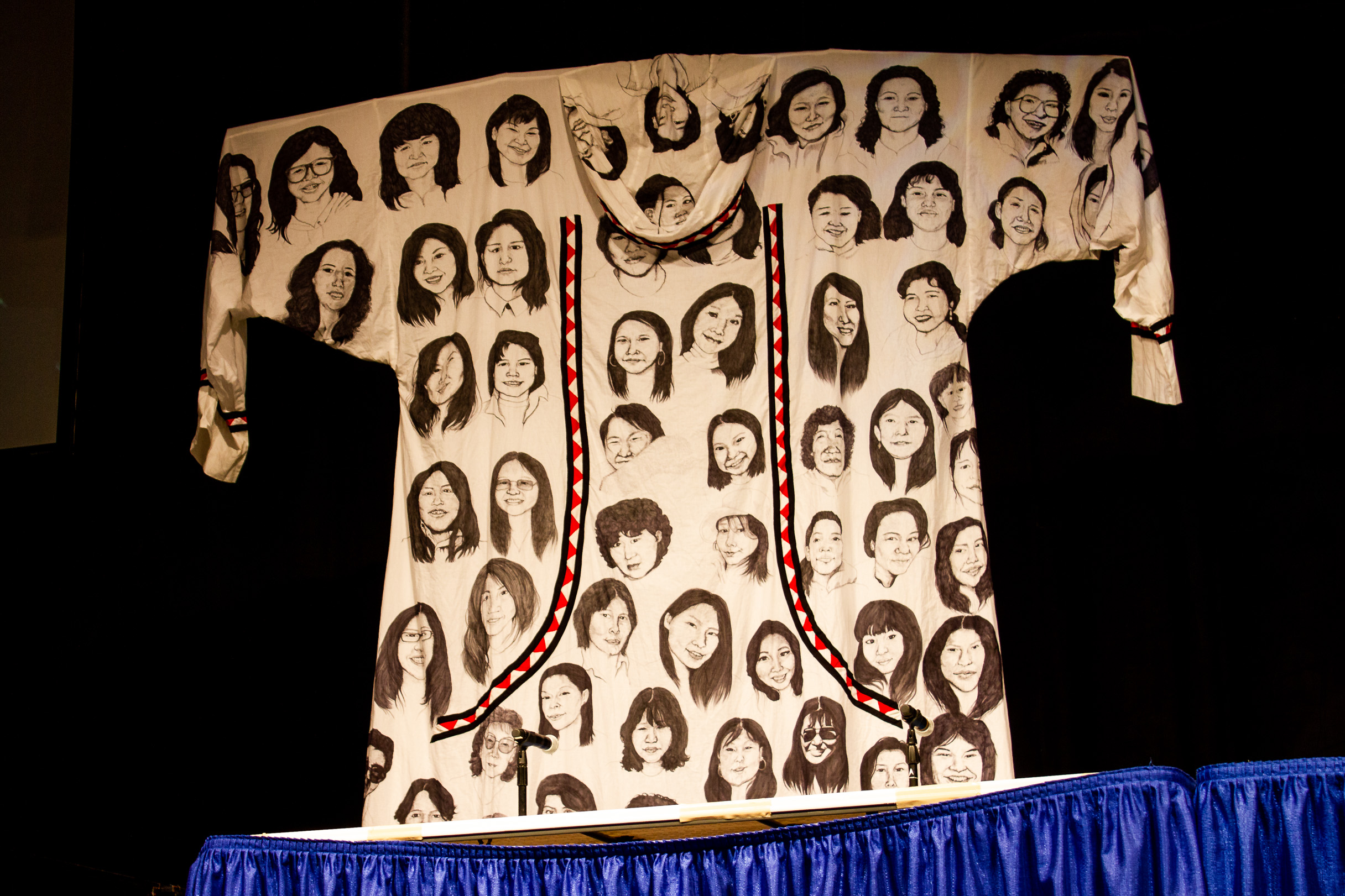 A photo of an art piece, a qaspeq with painted faces of women, hung at 2019 Alaska Federation of Natives.