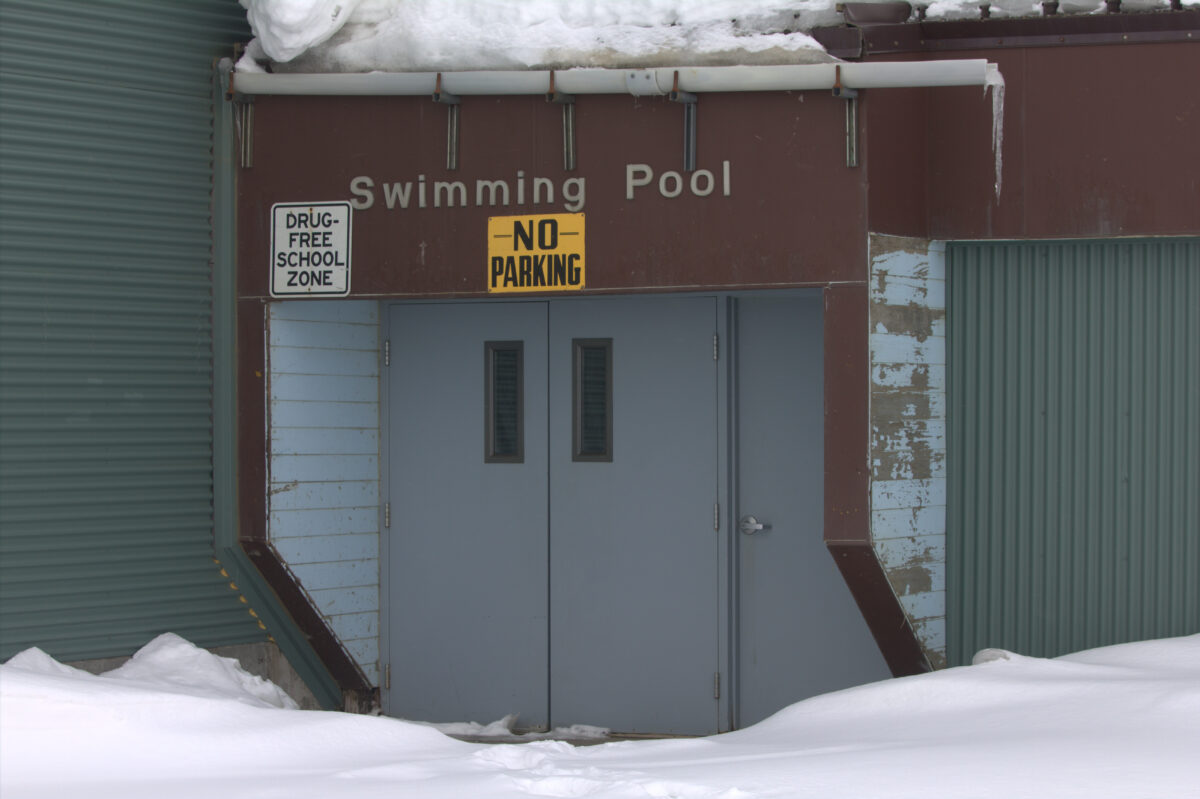 'No Parking' sign in front of Nome Swimming Pool entrance. This door leads to the tunnel that connects to Nome-Beltz High School. Photo from Joe Coleman, KNOM (April, 2020).