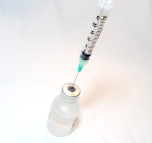 A syringe with the needle inside a vaccine bottle