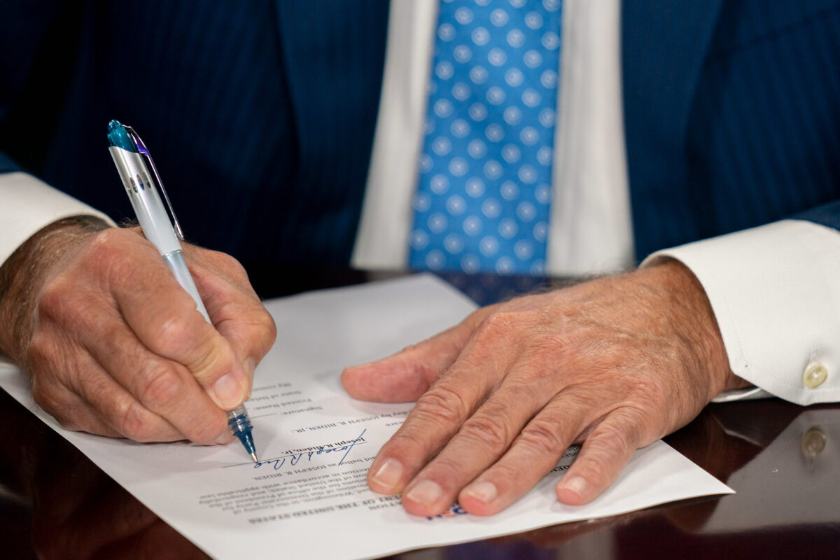 President Biden's hands sigining paperwork