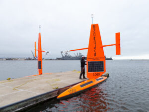 a dock with a man inspecting a saildrone.