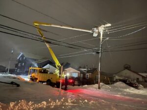 A bucket truck operating at night in the winter.