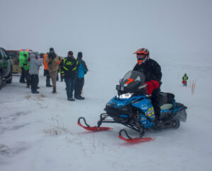 member of Iron Dog team 7 on the sea ice with crowd gathered behind