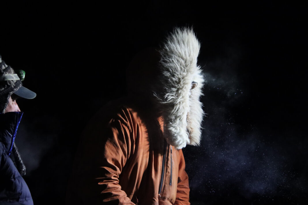 Profile of man wearing fur hooded coat racing at night time