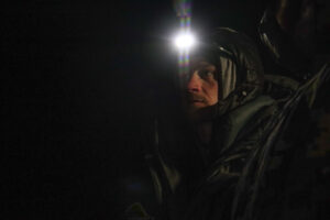 Headshot of man who is wearing a headlamp. It is night time.
