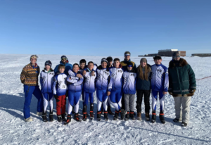 Ski team students lined ip outside in snow with coaches